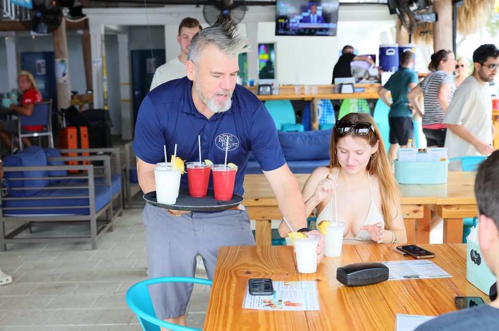 A man is serving drinks to a woman at a table in a bar.