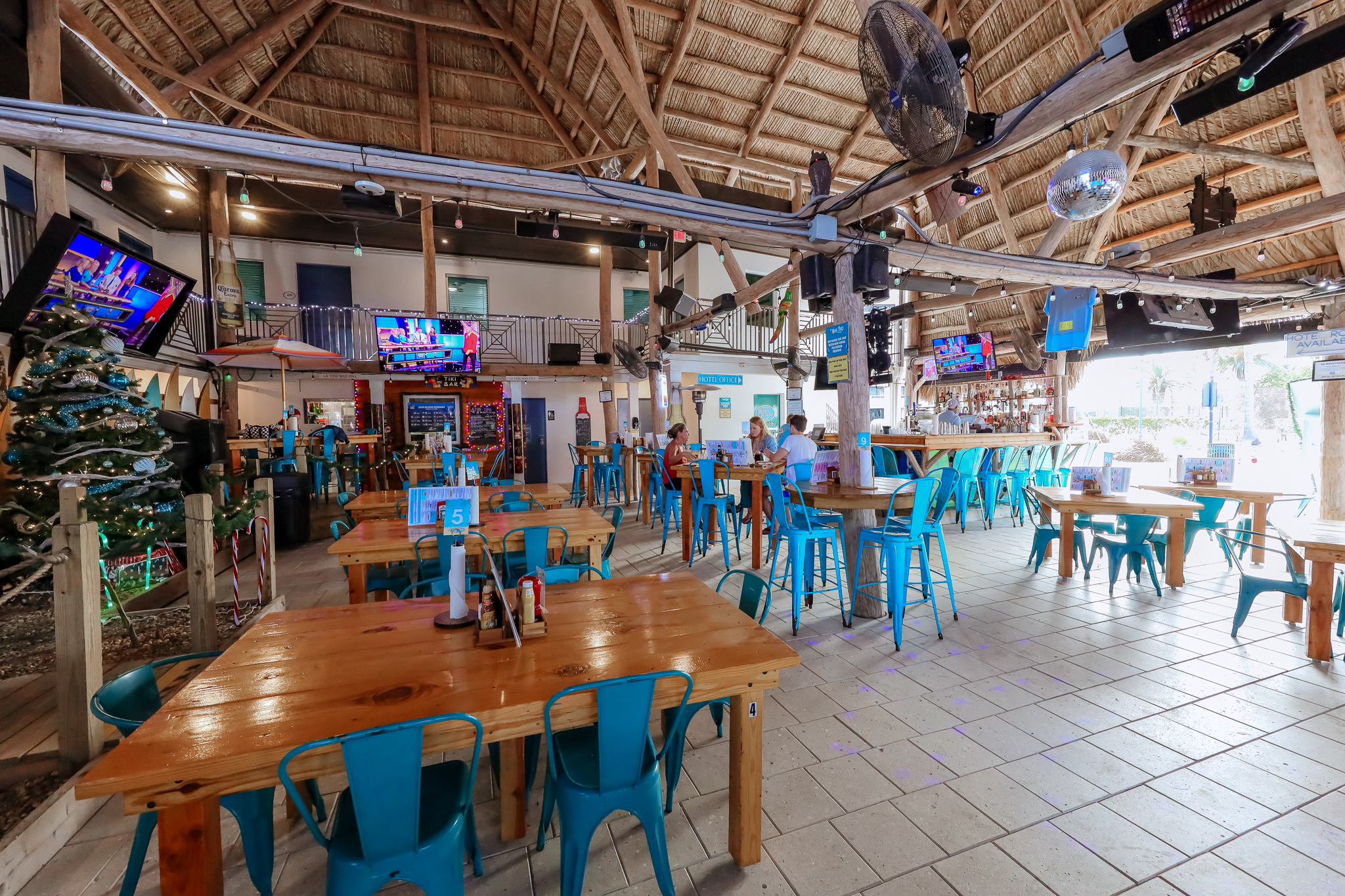 a large indoor dining area with wooden tables and blue chairs