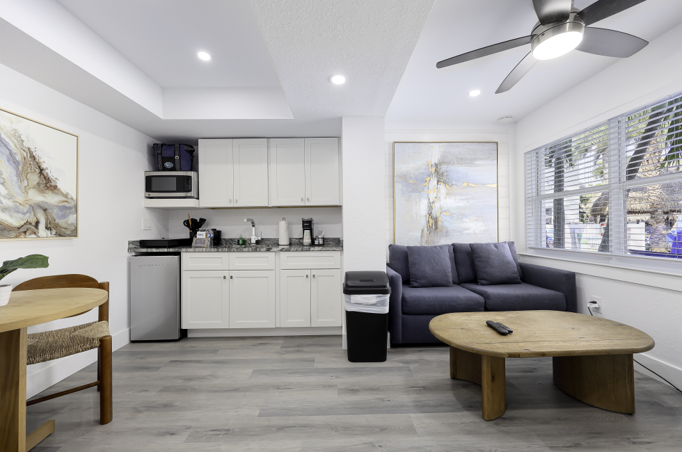 A wide view of a suite's living area with kitchenette, sofa, coffee table, and dining table.