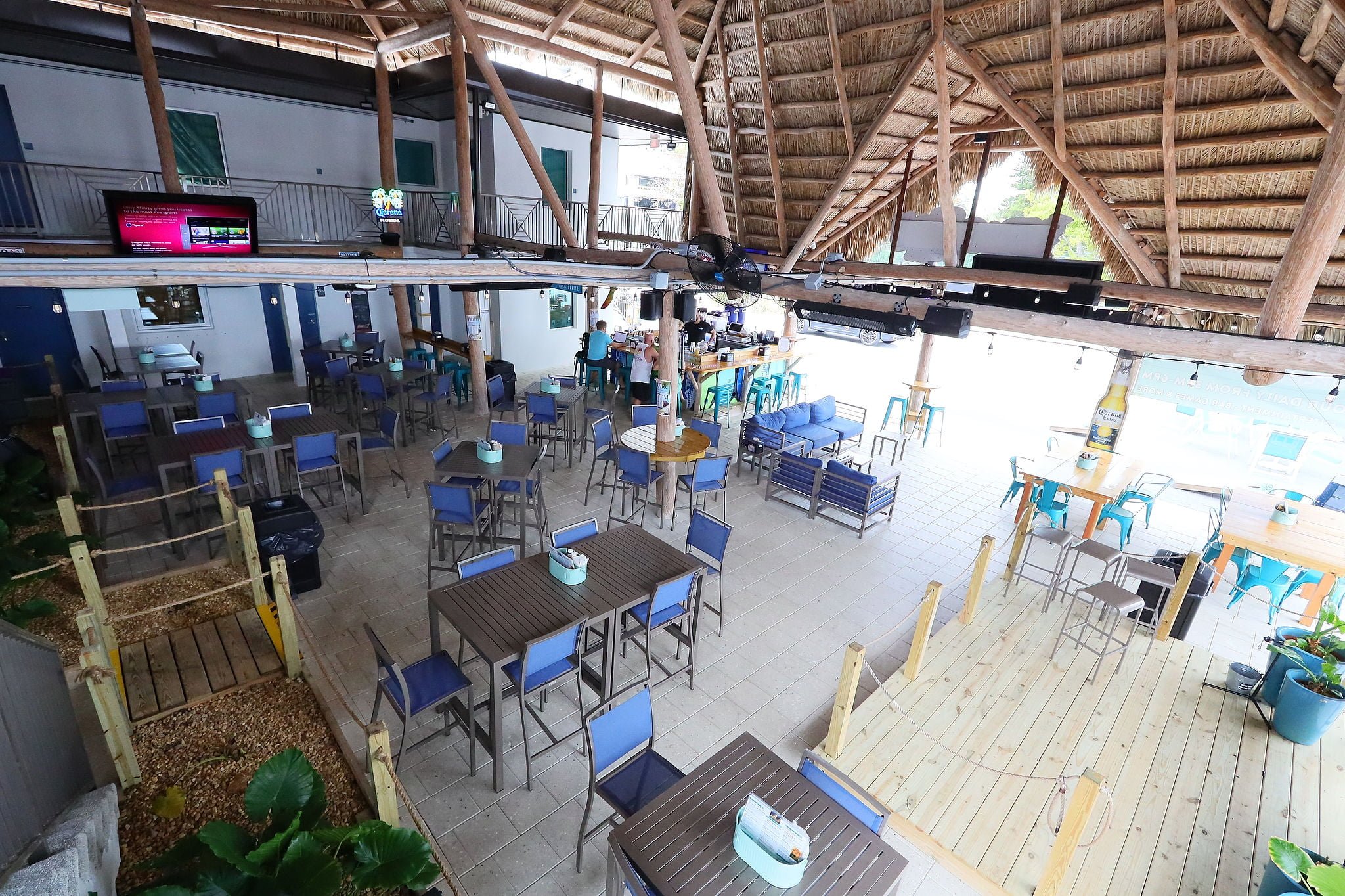 a large indoor dining area with tables and chairs, a bar, and a TV screen