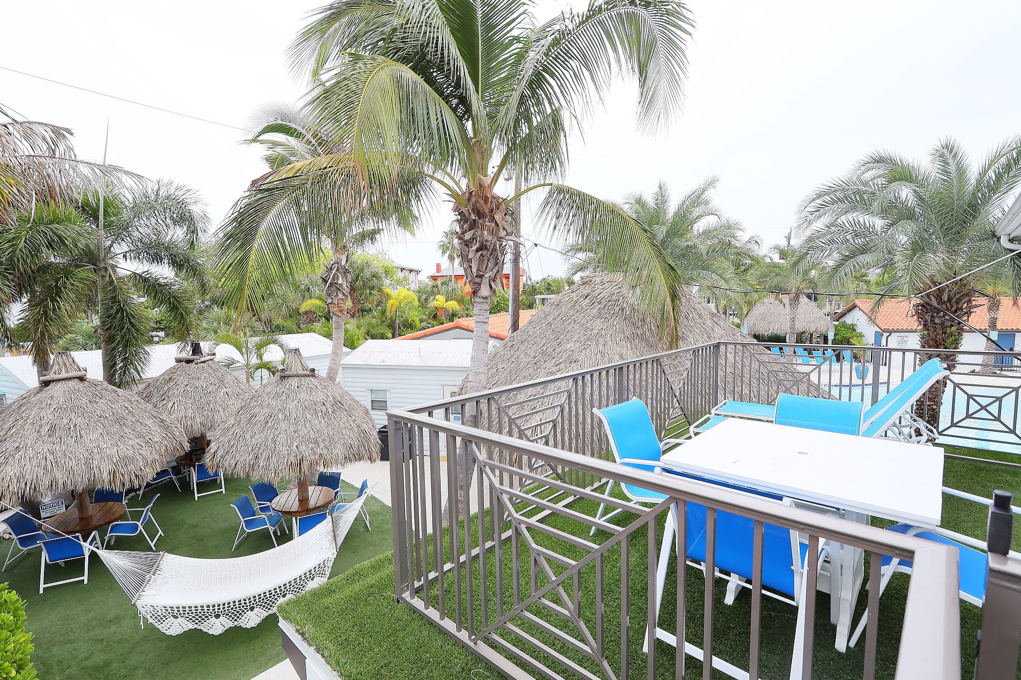 A tropical outdoor space with palm trees, outdoor seating, and grass.